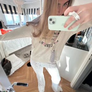 Beige sweatshirt med tryck - Säljer en beige ZADIG sweatshirt med färgglatt tryck framtill. Tröjan har långa ärmar och en avslappnad passform. Perfekt för en casual look.