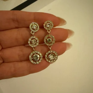 Rose glittriga örhängen med stenar - Eleganta guldrose glittriga örhängen med tre runda hängen, varje dekorerat med en klar sten i mitten. Perfekta för att ge en glittrig touch till din outfit. Saknas en mini sten.