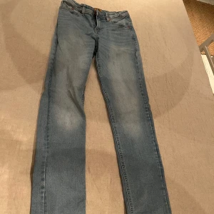 Blå jeans från Jack & Jones - Snygga blå jeans från Jack & Jones, modell Slim Glenn. De har en slim passform och klassisk femficksdesign med dragkedja och knapp. Perfekta för en stilren look.