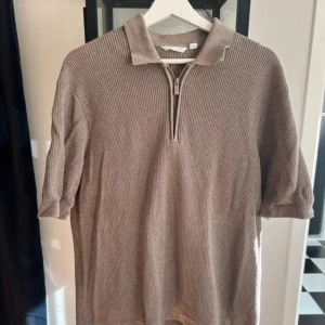 Beige ribbad pikétröja Dobber - Säljer en stilren beige pikétröja med ribbad struktur och dragkedja framtill ifrån Dobber!
