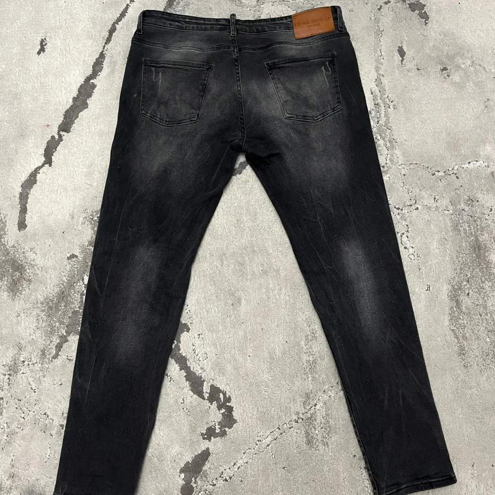 Snygga svarta jeans från Dsquared2 med slitna detaljer och en cool tvättad look. De har en klassisk femficksdesign och knappgylf. Perfekta för en trendig stil. Byxorna är storlek 56 och om ni vill ha några mer bilder eller om ni har några frågor är det bara att skriva. Farkut & Housut.