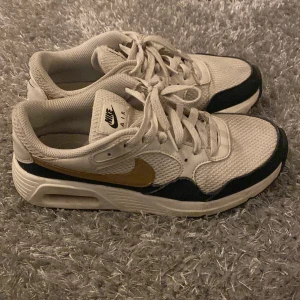 Nike Air sneakers - Snygga Nike Air sneakers i beige med svarta och guldiga detaljer. Skorna har en klassisk design med snörning. Pris kan diskuteras!