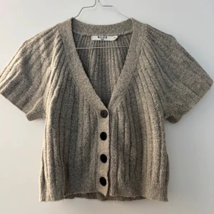 Beige ribbad kofta från NA-KD - Jätte fin beige kofta från NA-KD med korta ärmar och ribbad design. Storlek xxs men passar mig som brukar ha s❤️