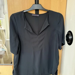 Svart topp som funkar både till fest och vardag! - Svart t-shirt topp från M&S med en elegant urringning vid halsen. Superbra skick. 