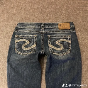 Lågmidjade bootcut jeans  - FRI FRAKT!! Säljer ett par snygga blå jeans med broderade bakfickor och vita stygn. De har en låg midja och en bootcut-stil. Jeansen har slitna detaljer på framsidan och är i fint skick! Midjemått 38 Innerbenslängd 83. 💕 Jag är 165