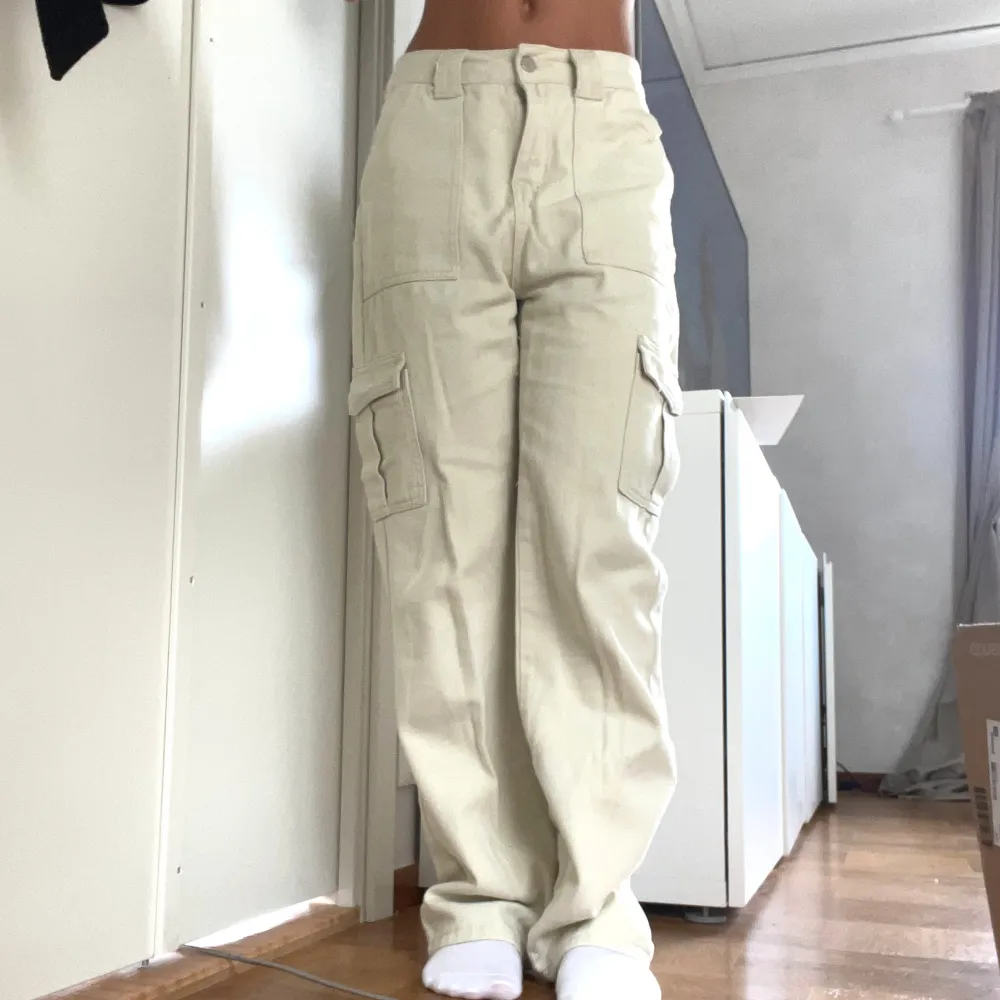 Säljer ett par snygga beige cargobyxor med hög midja. De har flera praktiska fickor på sidorna och en loose passform som ger en avslappnad stil. Perfekta för både vardag och äventyr!. Farkut & Housut.
