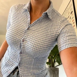 Blå skjorta - Figurnära skjorta i ljusblå/vit med struktur och knappar. Frakt tillkommer på 58kr 🫶🏻