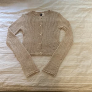 Beige stickad kofta - Säljer en superfin beige stickad kofta med knappar framtill. Den är croppad och har långa ärmar, perfekt för höst och vår. Koftan är i nyskick och passar både till vardags och fest. Så mysig och stilren!
