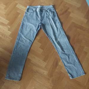 Säljer ett par grå jeans från Jack & Jones i modellen Loose/Chris. De har en loose passform och är tillverkade i ett slitstarkt denimtyg. Perfekta för en avslappnad stil. De har klassiska fem fickor och stängs med dragkedja och knapp.