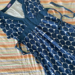 Blå och vit klänning från Purple - Säljer en superfin blå och vit klänning från Purple. Den har ett coolt prickigt mönster och en v-ringad hals. Klänningen är kortärmad och har knytband i midjan för en snygg passform. Perfekt för sommarens fester eller en dag på stan!