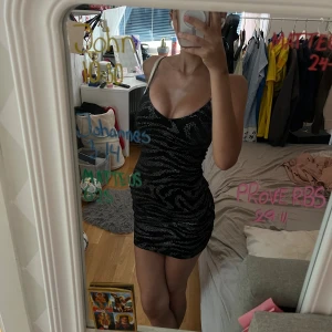 Kort klänning med glitter <3 Passande till nyår! - En kort svart klänning med tunna bekväma ärmar som är stretchiga. Tyget har en silkig vibe med glittriga mönster runt klänningen.   Bust: 60 cm Midja: 49cm Hip: 53 cm Längd: 76 cm Rem längd: 39 cm 