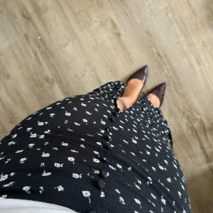 Blommig kjol - Svart kjol med vita små blommor🌸 slit i fram samt dragkedja på sidan🤍 Kjolen är från H&M i storleken 38✨