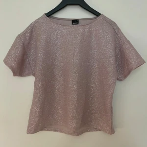 Glittrig rosa topp - Säljer en superfin glittrig rosa topp som är perfekt för festliga tillfällen. Den har korta ärmar och en bekväm passform. Toppen är i nyskick och redo att ge lite extra glitter till din garderob! ✨