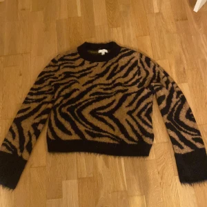 Stickad tröja med tiger mönster - En skön stickad tröja med tiger mönster i storlek xs men passar även s! Nästan helt oanvänd men inte köpt nyligen🥰Svårt att ta en ordentlig bild men sitter finare på! Även lite, lite ljusare i verkligheten.