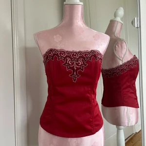 Korsett topp - Korsett topp med fin röd färg och vita detaljer🌹spänns där bak🤍 står inte storlek men sitter som en M