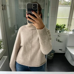 Beige stickad tröja - Säljer en supermysig beige stickad tröja med hög krage. Perfekt för kyliga dagar och passar både till vardags och lite finare tillfällen. Tröjan har långa ärmar och en avslappnad passform. Den är i bra skick och redo för en ny ägare!