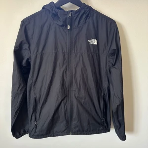 Vindjacka the North Face - En snygg vindjacka från märket The North Face. Jackan är i bra skick och inga defekter förekommer. Perfekt till en vindig höstdag.