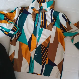 Färgglad mönstrad skjorta från Shein - Säljer en supercool skjorta från Shein i storlek M. Den har ett färgglatt geometriskt mönster i turkos, brun, vit och orange. Skjortan har långa ärmar och knappar framtill. Perfekt för att liva upp garderoben! 🌟
