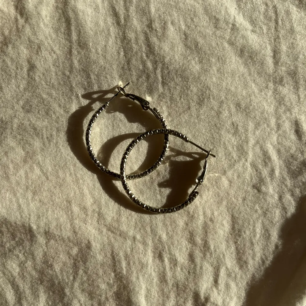Säljer tre par snygga örhängen i silverfärg. 35kr/styck Ett par med rosdesign och detaljerade blad, ett par med en elegant twistad form (som evighetstecknet) med glittriga stenar, och ett par klassiska creoler med en glittrig yta. Perfekta för att piffa upp vilken outfit som helst! 🌟. Asusteet.