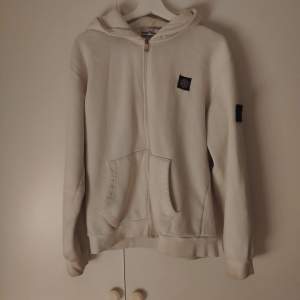 Säljer en snygg vit zip hoodie från Stone Island. Den är i bra skick och superbekväm att ha på sig. Passar perfekt till höst och vår! Sitter perfekt som M. Priset är inte hugget i sten!