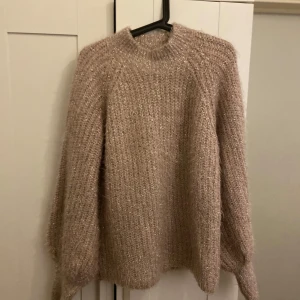 Beige stickad tröja - Mysig beige/ros färg stickad tröja med glittriga detaljer. Perfekt för kyliga höst- och vinterdagar. Tröjan har en normal passform och långa ärmar, vilket gör den både bekväm och stilren. Ett måste i garderoben för den som älskar att hålla sig varm och trendig💕
