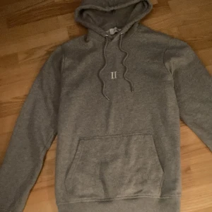 Grå les deux hoodie - Säljer en grå hoodie i bra skick med ett stilrent vit tryck på bröstet. Perfekt för höst och vinter och enkel att matcha med allt. Priset inte hugget i sten!