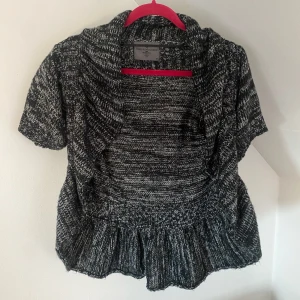 Svart och vit stickad bolero  - Säljer en superfin svart och vit stickad kofta/bolero med korta ärmar. Varsamt använd och i väldigt bra skick
