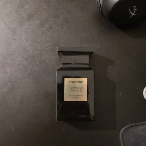 Tom Ford Tobacco Vanille Eau de Parfum - Säljer en lyxig Tom Ford Tobacco Vanille Eau de Parfum. Flaskan är elegant och svart med en guldig etikett. Perfekt för den som älskar en varm och kryddig doft med inslag av tobak och vanilj. Kommer med originalförpackning. Perfekt för både vardag och speciella tillfällen.  100ml runt 95 kvar.