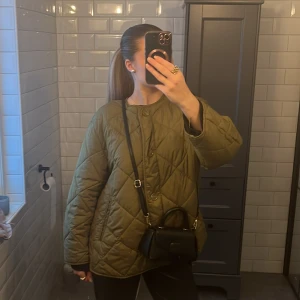 Olivgrön quiltad jacka - Säljer en olivgrön quiltad jacka i mycket bra skick. Den har en oversized passform och långa ärmar, perfekt för höst och vår. Jackan har knappar framtill och en stilren design som passar till det mesta. Supermysig och trendig!