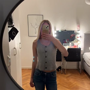 Grått linne med knappar, oanvänd  - Säljer ett snygg grått linne med knappar framtill. Helt oanvänd