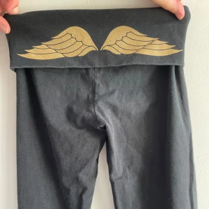 Victoria's Secret Yoga Pants -  Säljer ett par svarta byxor från Victoria's Secret i storlek XS. De har en låg midja med ett coolt vingmönster i guld på baksidan🫶🏼skriv om ni har frågor🫶🏼säljer pga att de inte kommer till användning🫶🏼
