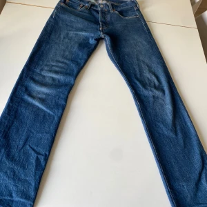 Levi's 501 Jeans - Säljer ett par klassiska Levi's 501 jeans i blå denim. De har en rak passform och är i mycket bra skick då de knappt är andvända. Ny pris 1200kr mitt pris 449kr!!!!