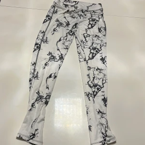 Mönstrade leggings från Lindex - Säljer ett par coola leggings från Lindex i storlek 146/152. De är vita med ett svart abstrakt mönster som ger en unik look. Perfekta för både vardag och idrott tillfällen. Superbekväma och stretchiga!