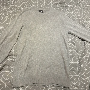 Grå tröja från H&M - Säljer en stilren grå tröja från H&M i slim fit. Perfekt för både vardag och lite finare tillfällen. Tröjan är långärmad.