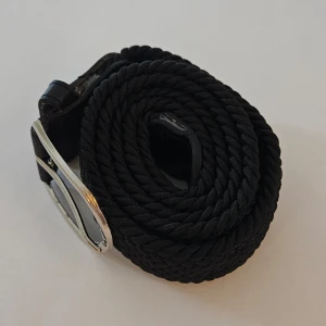 Svart flätat bälte - Säljer ett snyggt svart flätat bälte med silverfärgat spänne. Perfekt för att ge en stilren touch till vilken outfit som helst. Bältet är i mycket bra skick och passar både till vardag och fest. Ett måste i garderoben! 🖤