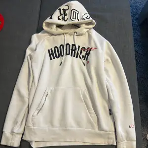 Säljer en snygg vit hoodie från Hoodrich med svart text på framsidan och coola detaljer på huvan. Den har en stor ficka fram och text på ryggen. Perfekt för en avslappnad stil eller streetwear-look. Passar både höst och vår! Köpt på JD-sports i Leicester, UK. Storlek S/M.