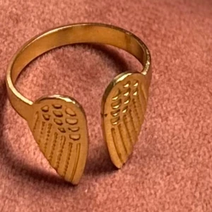 Guldfärgad ring med  vingar  - Säljer en guldfärgad ring med vingar från lyla. Bra skick justerbar.🪽⭐️
