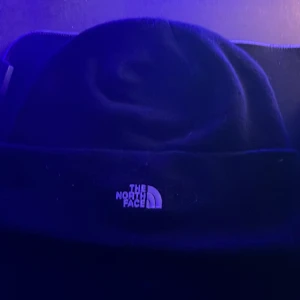 Svart mössa från The North Face - Säljer en svart mössa från The North Face i nytt skick. Den är perfekt för kalla dagar och har en stilren design med loggan broderad framtill. Materialet känns mjukt och bekvämt, vilket gör den idealisk för både vardag och utomhusaktiviteter.