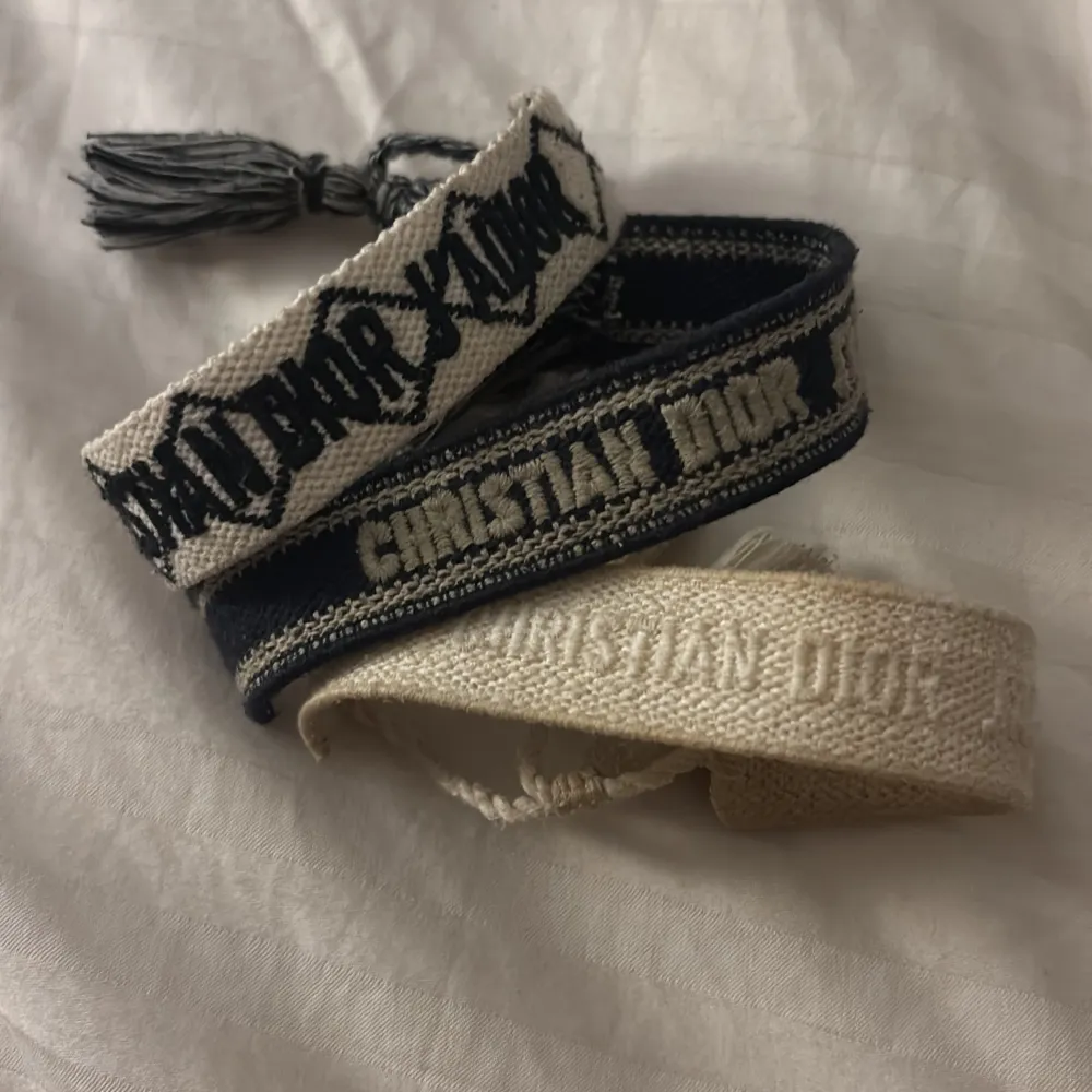 Säljer tre snygga armband i olika färger. Ett är beige med vit text, ett är mörkblått med beige text och det sista är beige med mörkblå text. De har en trendig och elegant design med tofsdetaljer. Perfekta för att ge din outfit en lyxig touch! Köp alla för 400. Accessoarer.