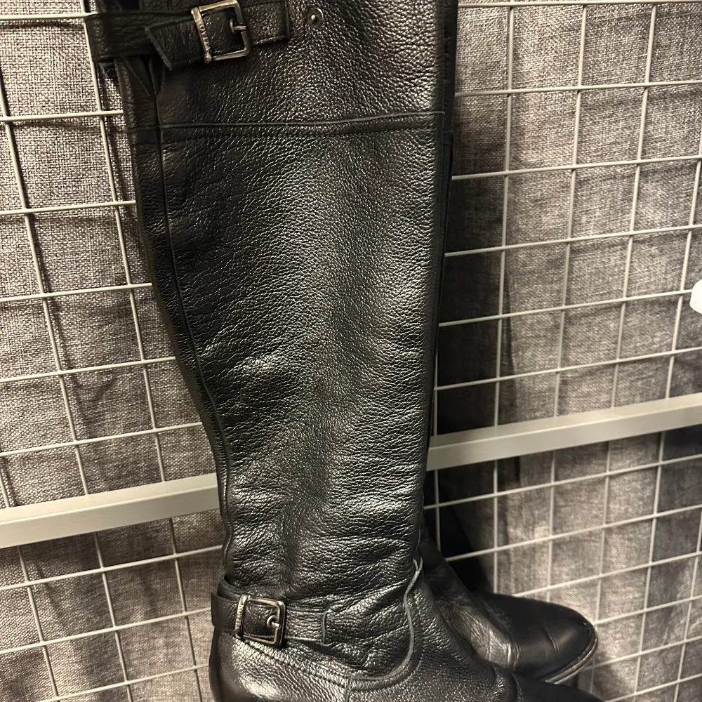 Snygga svarta stövlar i skinn med dekorativa spännen upptill och vid ankeln. Perfekta för höst och vinter, dessa stövlar är både stiliga och praktiska. De har en klassisk design som passar till många olika outfits. Från Scorett strl 37 nypris 2500kr. Använda men i fint skick! Overkneemodell. Väldigt fint lite grövre läder. Säljes pga ändrad storlek.. Kengät.