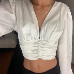 Vit blus - Säljer en elegant vit blus med långa ärmar och knappar framtill. Den har en v-ringad design och är croppad🫶🏻🫶🏻