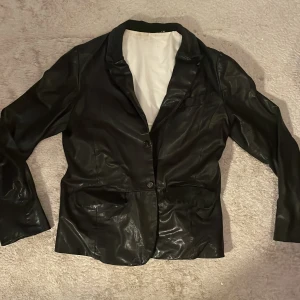 Vintage skinnjacka från Hope - Säljer en snygg, vintage, svart skinnjacka från Hope i bra skick. Jackan har en klassisk design med knappar framtill och en stilren look. Perfekt för höst och vår, och funkar både till vardags och fest. Storleken är XS och den har en normal passform. Passa på att uppgradera din garderob med denna stiliga jacka!