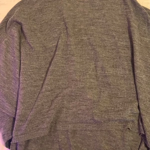 Grå stickad tröja - Mysig grå stickad tröja i bra skick. Perfekt för kyliga höst- och vinterdagar. Tröjan har en enkel design med ribbade kanter som ger en klassisk look. Passar både till vardags och lite mer avslappnade tillfällen.20