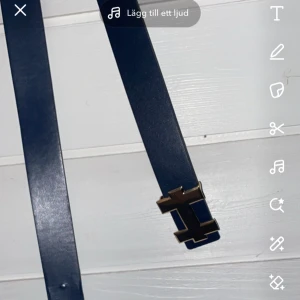 Blått bälte med metallspänne - Snyggt blått bälte i skinn med ett stilrent metallspänne i guld. Perfekt för att ge en touch av elegans till vilken outfit som helst. Passar både till vardags och fest. Ett måste i garderoben för den stilmedvetna!