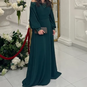 Mörkgrön långklänning med pärldetaljer - Elegant mörkgrön långklänning med offshoulder-design och vackra pärldetaljer vid hals och ärmslut. Perfekt för festliga tillfällen. Klänningen har långa ärmar och en flytande passform. Den är köpt i en butik i Turkiet! Jätte fina detaljer och passar bra till balen! Passar även strl S