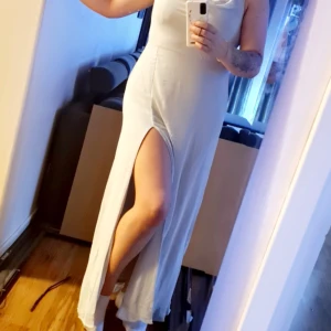 Ljusblå långklänning med slits - Säljer en elegant ljusblå långklänning med en stilren slits på sidan. Perfekt för sommarens fester eller bröllop. Klänningen har en ärmlös design och är gjord i ett mjukt och bekvämt material. Den medföljande sjalen ger en extra touch av elegans.