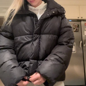 Svart vinterjacka  - Säljer en svart pufferjacka i mycket bra skick. Den är perfekt för kalla dagar med sin tjocka vaddering och dragkedja framtill. Jackan har en hög krage och långa ärmar för extra värme. Passar perfekt till vinterns kyliga väder!