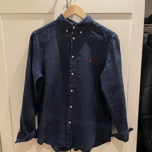 Mörkblå skjorta från Ralph Lauren - Säljer en snygg mörkblå skjorta från Ralph Lauren i bomull. Den har långa ärmar och knappar fram. Perfekt för både vardag och fest! Den klassiska designen gör den lätt att matcha med olika outfits. Skjortan är i mycket bra skick och redo för en ny ägare. Skriv gärna om ni några funderingar🤩💭