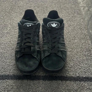 Svarta Adidas campus - Säljer ett par snygga svarta adidas campus i mocka. De har lite tecken på användning. de är perfekta för vintern då de är lite tjockare och varmare än vissa andra sneakers! Skorna är i bra/använt skick. 