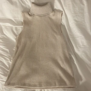 Polotopp  - Säljer ribbad polotopp från Zara. Den är ärmlös och har en hög polokrage. Toppen är i mycket bra skick💕💕😁
